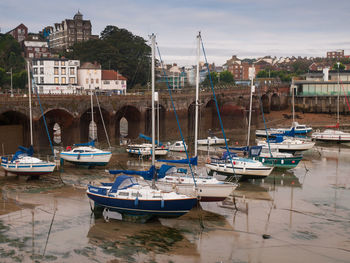 Boats moored at harbor against buildings in city