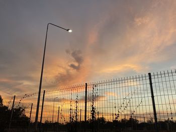 Low angle view of silhouette fence against sky during sunset