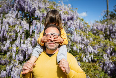 Child sits on father shoulder and closes his eyes