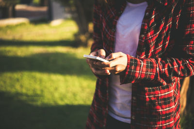 Midsection of woman using phone on field