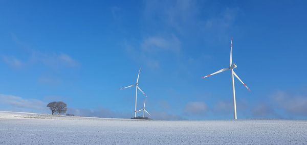 Wind turbines on land against blue sky
