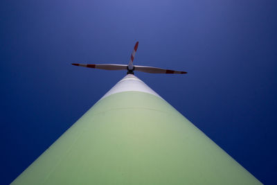 Directly below shot wind turbine against blue sky