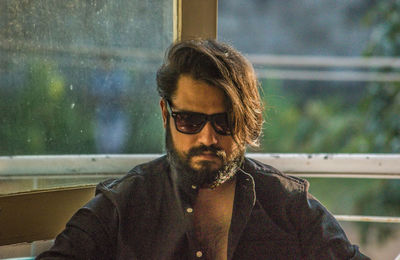 Portrait of young man sitting on window