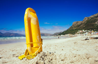 Close-up of yellow water on beach against blue sky