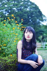 Beautiful young woman sitting against plants