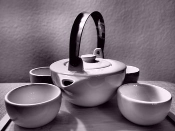Close-up of teapots with cups in tray at table