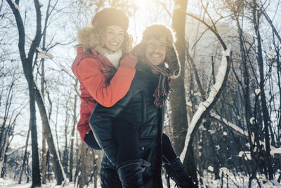 Woman with arms raised in forest during winter