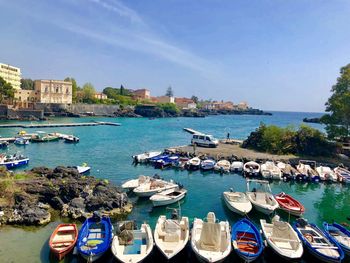 Boats moored in sea by city against clear sky