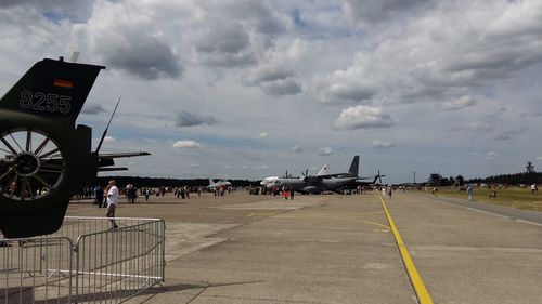 People at airport runway against sky