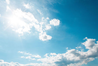 Low angle view of sunlight streaming through clouds