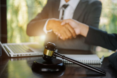 Midsection of lawyer holding gavel on table