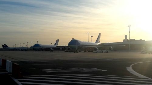 Airplane on airport runway against sky during sunset