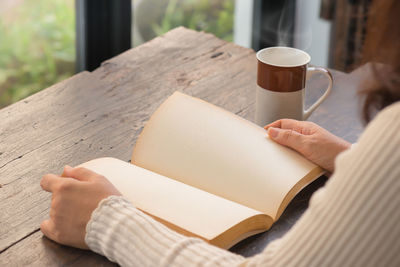 Low section of woman with coffee cup on table