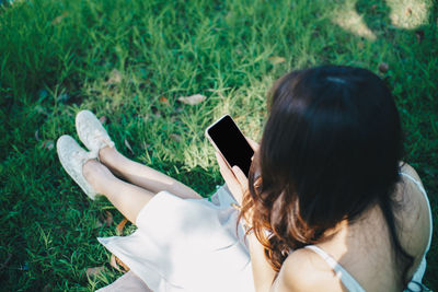 Midsection of woman using mobile phone in grass