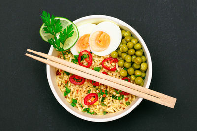 Beautiful noodle dish with green pea, eggs, red hot pepper and greens