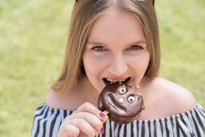 Close-up portrait of smiling young woman holding ice cream in field