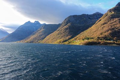 Scenic view of sea by mountains against sky