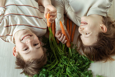 Boy and girl with carrot lying on floor