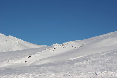 Scenic view of snowcapped mountains against clear blue sky