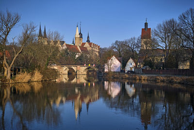 Arch bridge over river by buildings against sky