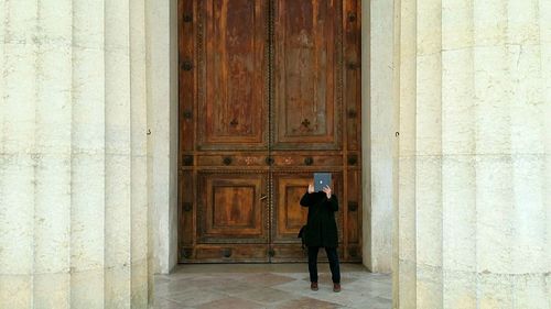 Rear view of woman standing against door