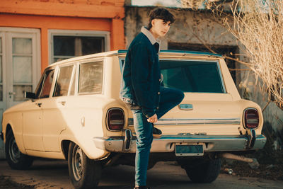 Trendy young man posing with retro styled car