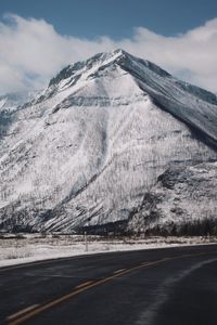 Road by snowcapped mountain against sky