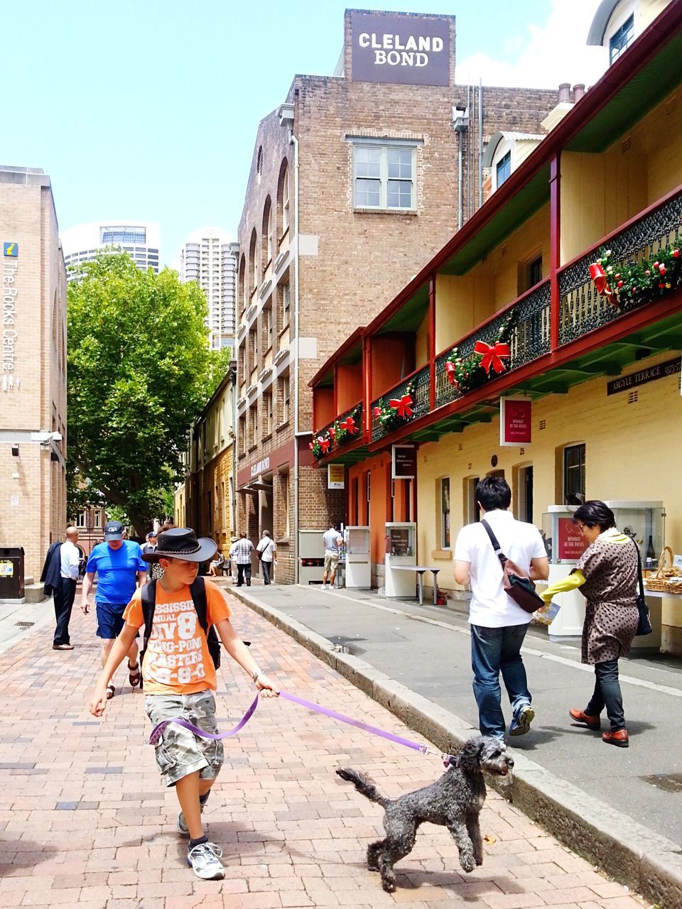 building exterior, architecture, built structure, city, street, lifestyles, walking, full length, men, person, city life, leisure activity, casual clothing, rear view, cobblestone, sidewalk, day, sunlight, city street