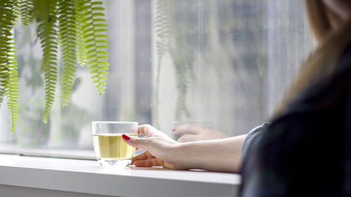 Woman drinking tea from glass window