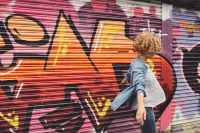 Young woman dancing against graffiti shutter