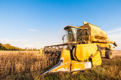 Agricultural machinery on field against blue sky