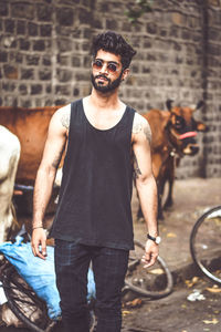 Thoughtful young man standing on footpath in city