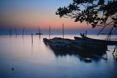 Boats moored in sea against sky during sunset