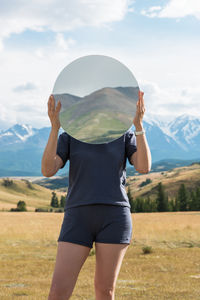 Rear view of woman standing on field against sky