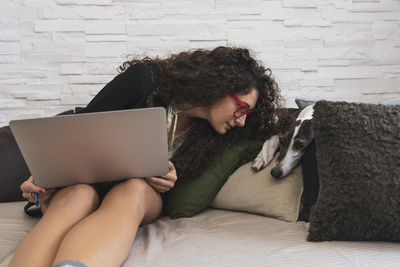 Young woman using laptop while sitting on sofa at home