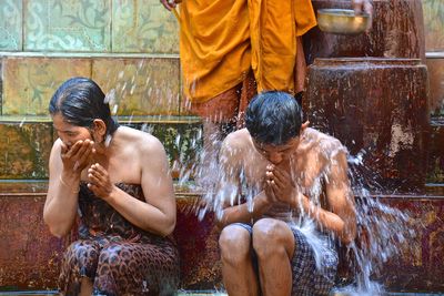 People bathing while sitting on steps