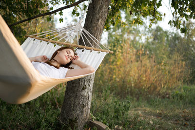 Young woman sitting on hammock in forest