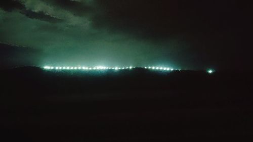 Illuminated landscape against sky at night