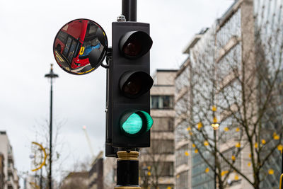 Green traffic light signal and traffic convex mirror with the reflection of the red bus