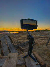 Coin-operated binoculars on field against clear sky during sunset