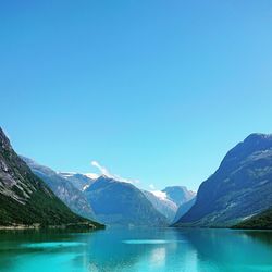 Scenic view of lake and mountains against clear blue sky
