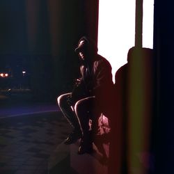 Side view of young man looking away while sitting on window