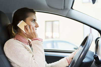 Side view of businesswoman using smart phone while driving car