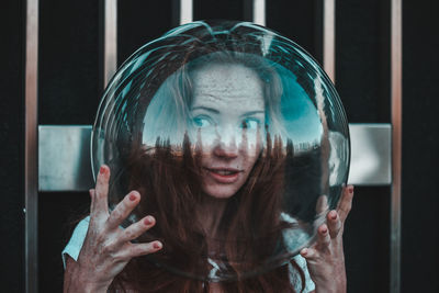 Thoughtful young woman wearing glass helmet in head against metallic railing