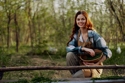 Portrait of smiling woman with food in basket at farm