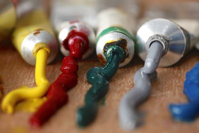 Close-up of colorful paints spilled from tubes on wooden table