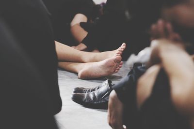 Low section of person with legs crossed amidst crowd on floor