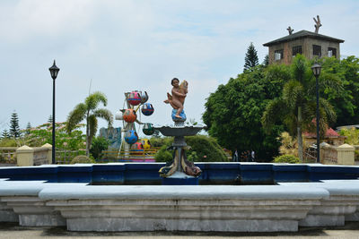 Statue by building against sky