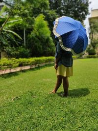 Rear view of woman holding umbrella on field