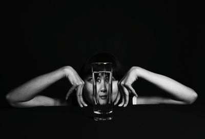Close up of woman seen through glass of water against black background
